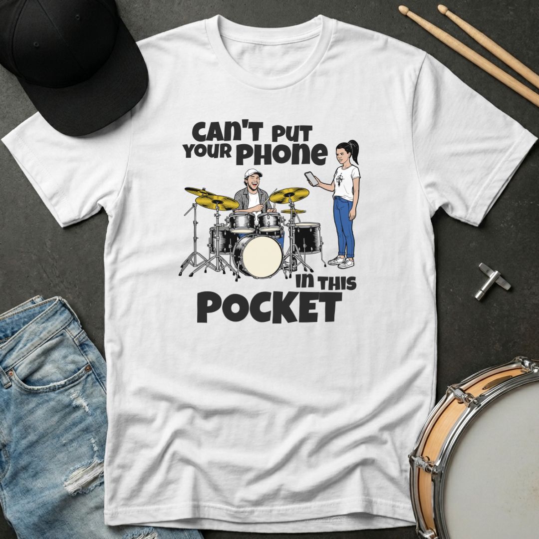 White t-shirt with a graphic design and text on a dark surface with drumsticks and jeans.
