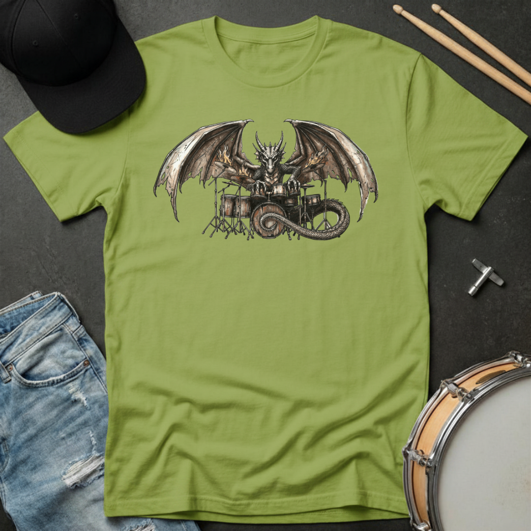 Green t-shirt with a dragon playing drums graphic on a dark surface with casual items.
