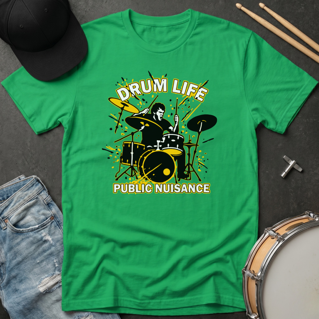 Green t-shirt with 'Drum Life Public Nuisance' graphic on a dark surface with drumsticks and a cap.