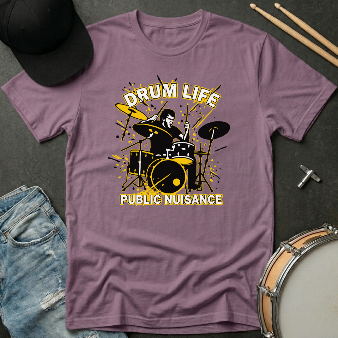 Purple t-shirt with drum design and text 'Drum Life Public Nuisance' on a dark surface with accessories.
