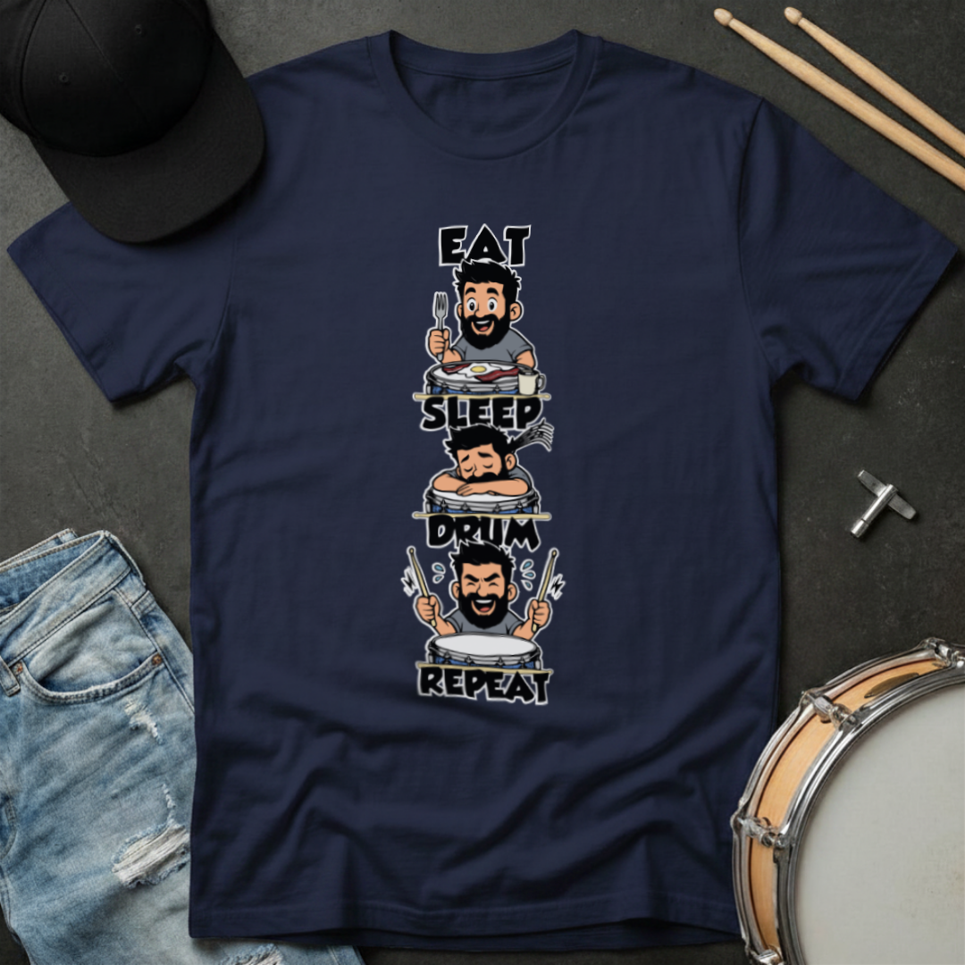 Navy blue t-shirt with a graphic design of a drummer and text 'Eat, Sleep, Drum, Repeat' on a dark surface with drumsticks and a cap.