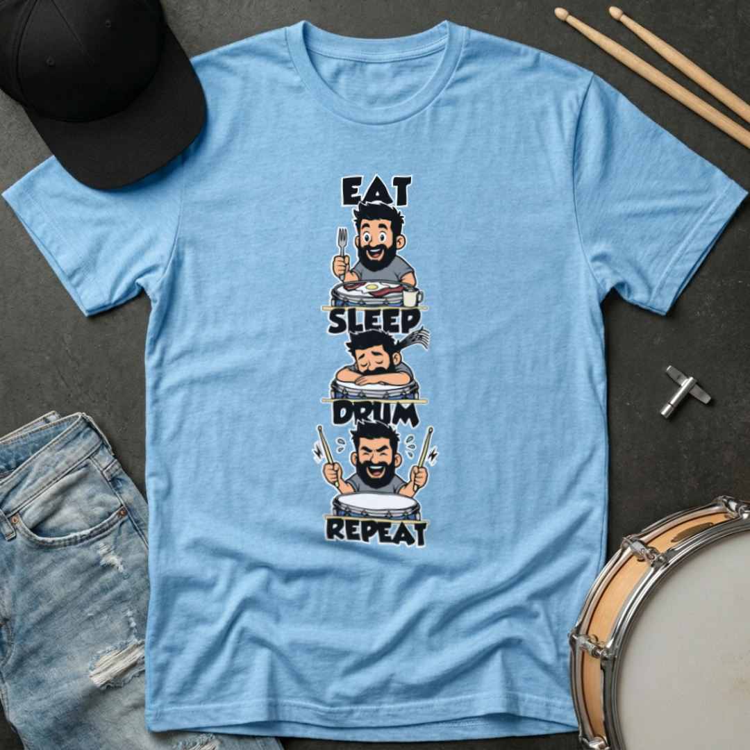 Blue t-shirt with a graphic design of a drummer and text 'Eat, Sleep, Drum, Repeat' on a dark surface with drumsticks and a hat.