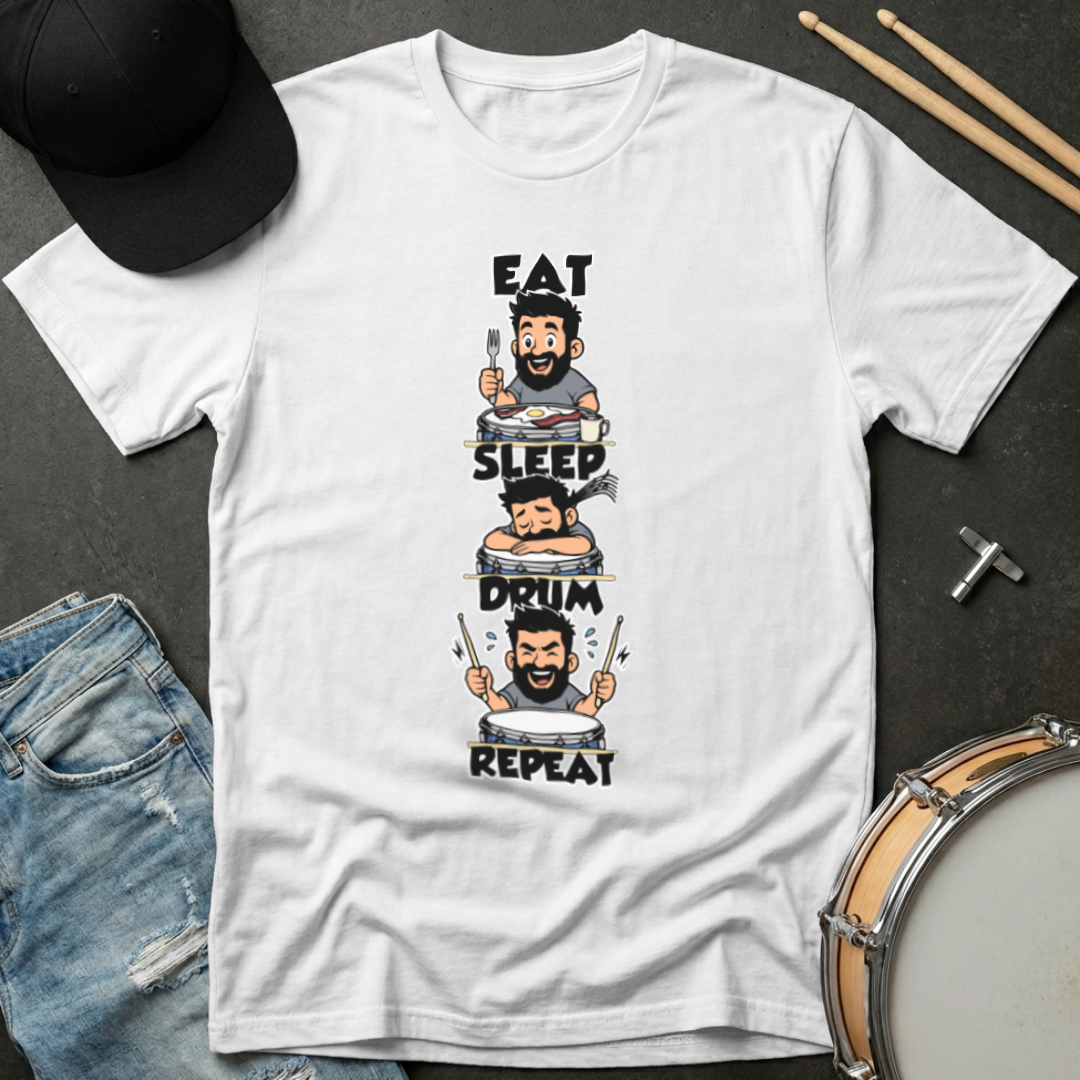 White t-shirt with a graphic design featuring a cartoon drummer and text 'Eat, Sleep, Drum, Repeat' on a dark surface with a cap and drumsticks.