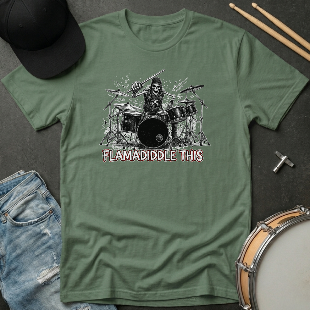 Green t-shirt with a graphic design of a person playing drums and text 'FLAMADIDDLE THIS' on a dark surface with casual items.