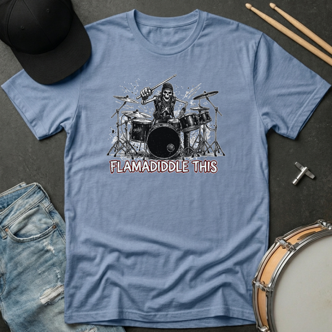 Blue t-shirt with a graphic of a skeleton playing drums and text 'FLAMADIDDLE THIS' on a dark surface with drumsticks and a cap.
