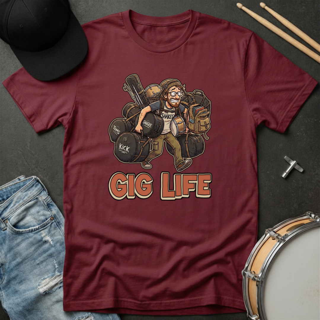 Maroon t-shirt with 'Gig Life' graphic featuring a drummer, surrounded by drumsticks, cap, jeans, and snare drum on a dark surface.