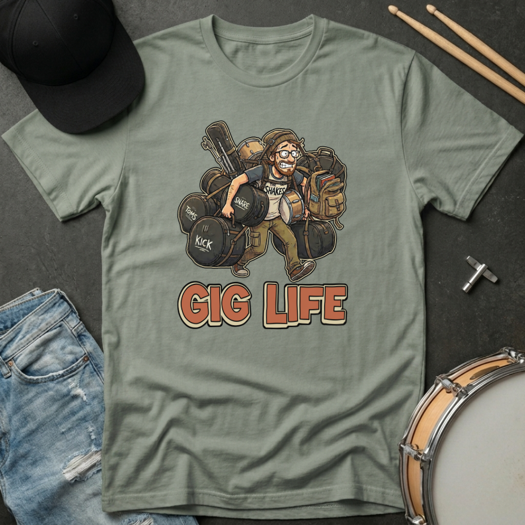 Green t-shirt with 'Gig Life' graphic design featuring a drummer, surrounded by drumsticks and a hat on a dark surface.