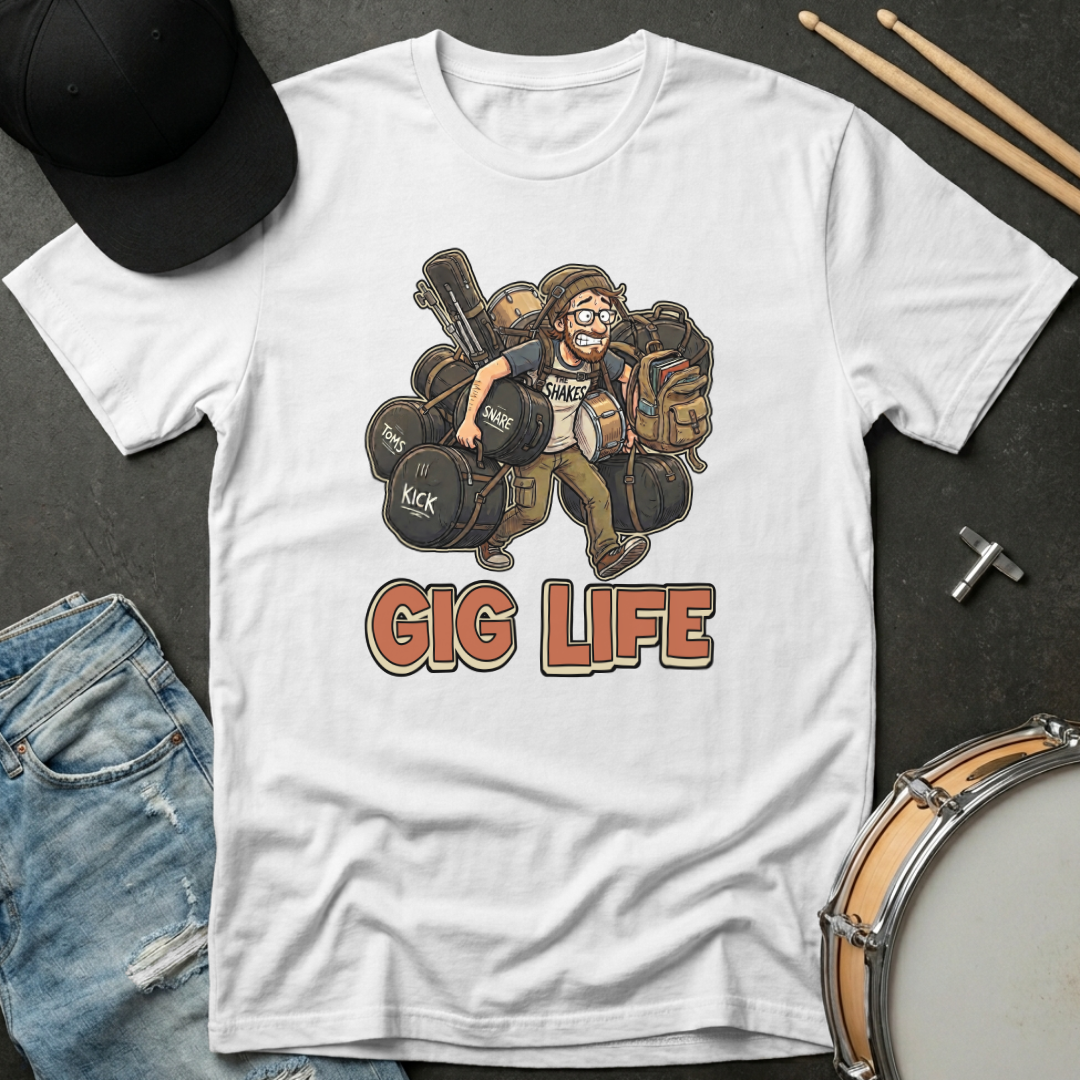 White t-shirt with 'Gig Life' graphic featuring a drummer, surrounded by drumsticks, jeans, and a hat on a dark surface.