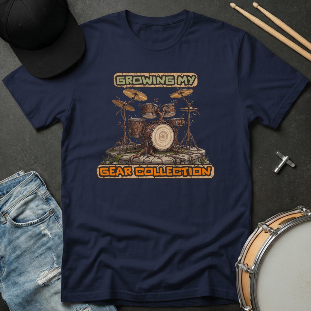 Navy blue t-shirt with drum set graphic and text 'Growing My Gear Collection' on a dark surface with accessories.