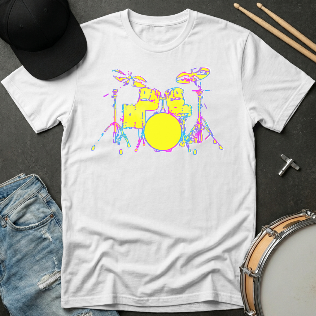 White t-shirt with colorful drum set design on a dark surface with casual items.