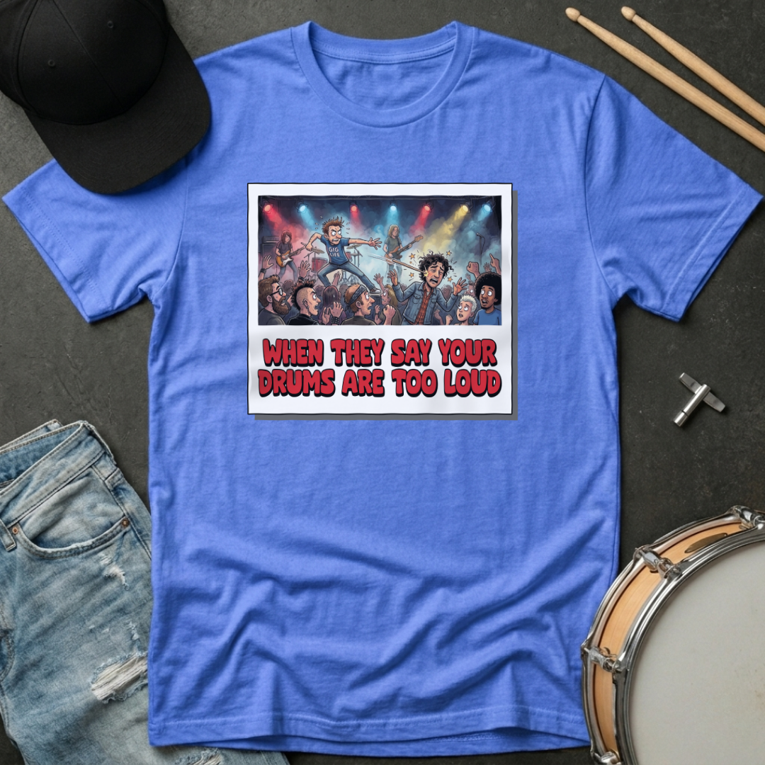 Blue t-shirt with graphic design and text, placed on a dark surface with drumsticks and a hat.