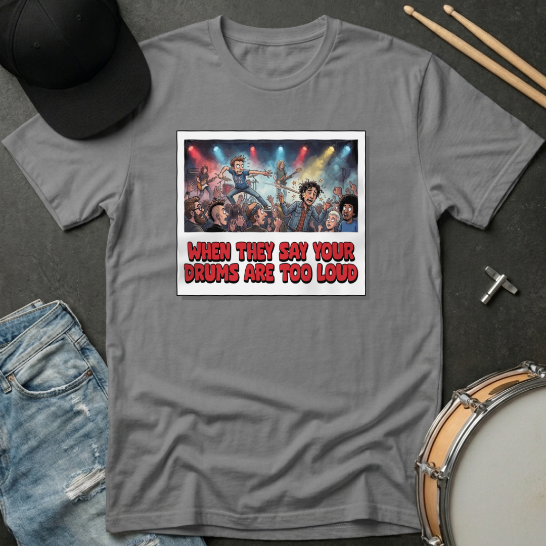 Gray t-shirt with graphic design and text, placed on a dark surface with a hat and drumsticks.