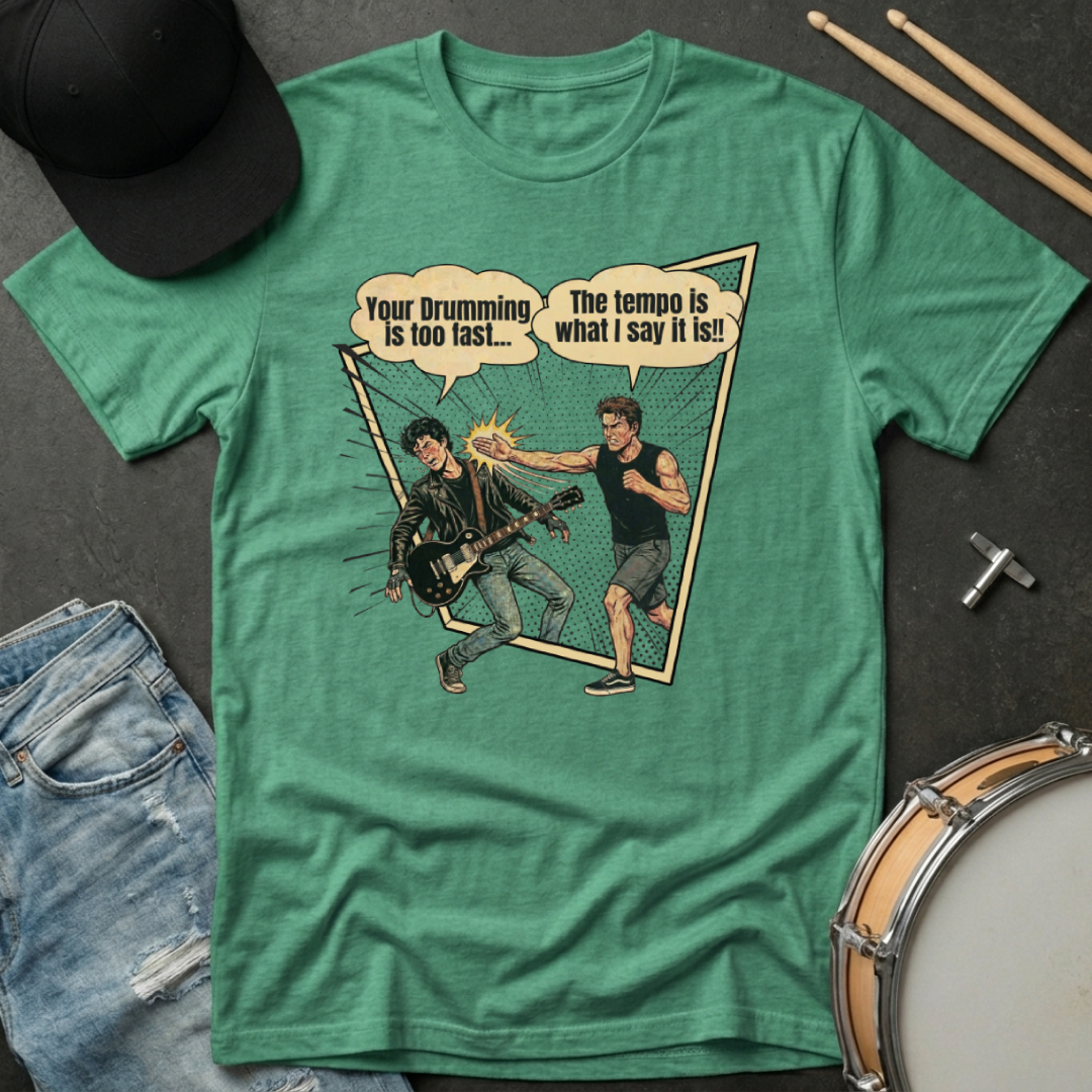 Green t-shirt with graphic design of two musicians and text, placed on a dark surface with drumsticks and a cap.