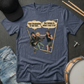 Blue t-shirt with graphic design of two musicians and text on a dark surface with drumsticks and jeans.