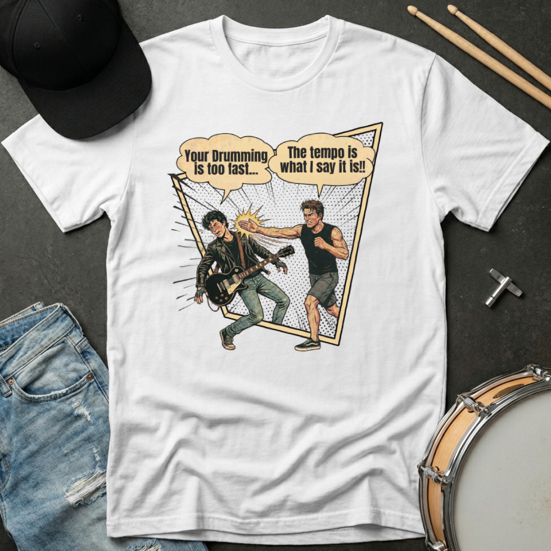 White t-shirt with graphic design of two musicians and text, displayed with a cap, jeans, and drumsticks on a dark surface.